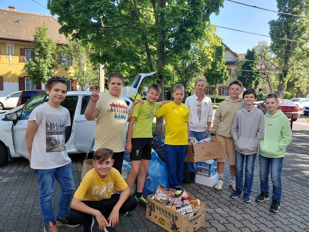 Iskolás fiúk az összegyűjtött adományokkal teli dobozok mellett