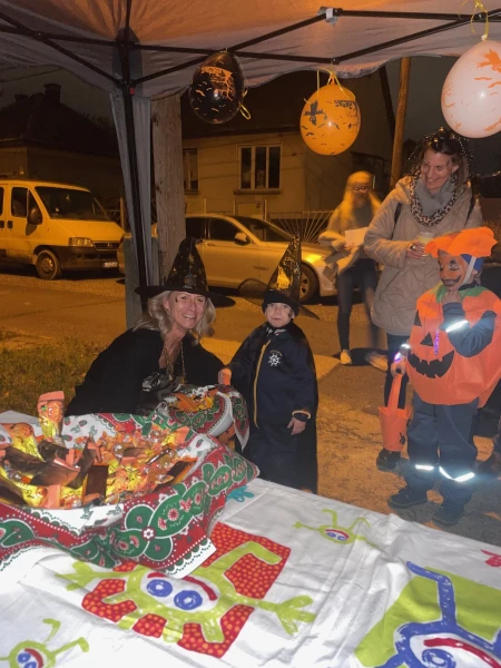 Jelmezes gyerekek egy sátor alatt felállított cukorkás asztalnál, este