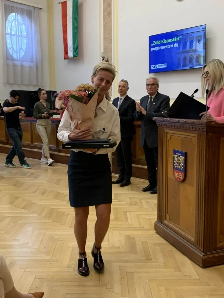 Az alapítvány képviselője a díjjal és egy virágcsokorral a díjátadón